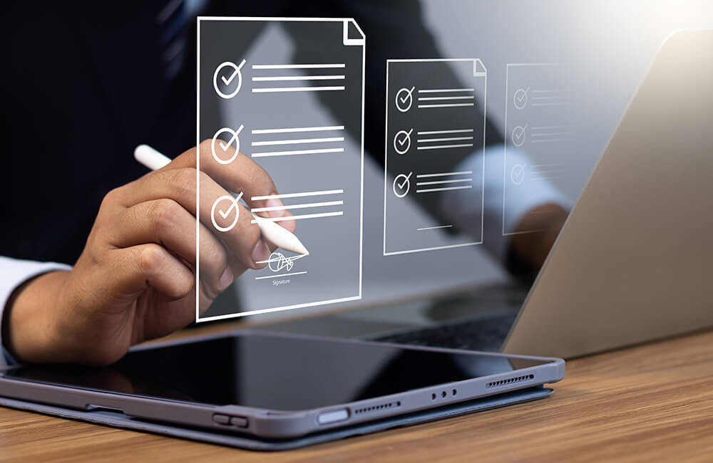Hand hält digitalen Stift über Tablet mit eingeblendeten, transparenten Checklisten und Unterschriftsfeld vor Laptop im Hintergrund.