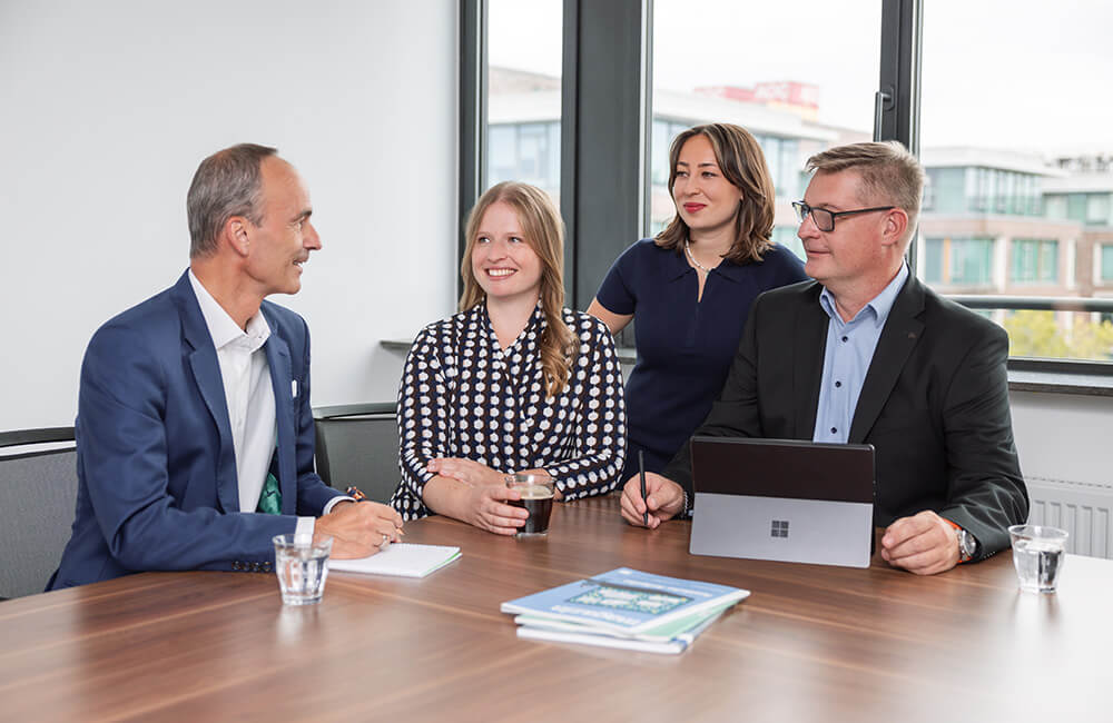 Vier Kolleginnen und Kollegen der Unigarant tauschen sich im Konferenzraum aus.
